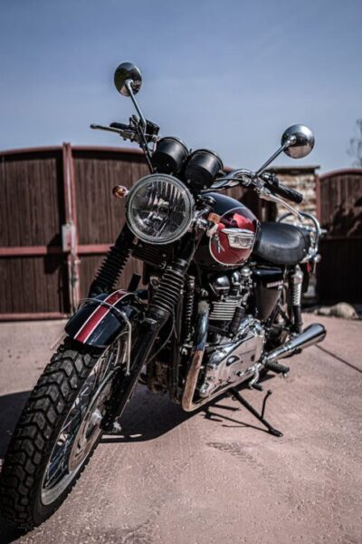 Black and red retro motorcycle with chrome details parked on asphalt road against cloudless blue sky